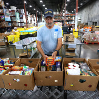 Volunteer Alfred Delio packs boxes of food in the warehouse at Second Harvest Food Bank