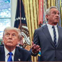 Donald Trump sits at his desk, left, in the oval office while Robert F Kennedy Jr stand behind him and speaks while gesturing