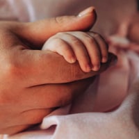 A close-up of a mother gently holding her baby's tiny hand,.
