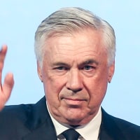 Carlo Ancelotti waves while holding a trophy on stage