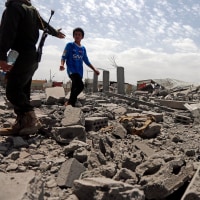 A security guard asks a child to stop walking over the rubble of a building destroyed by U.S. strikes on April 27, 2025 in Sana'a, Yemen. 