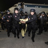 An alleged gang member escorted from a plane by El Salvador police