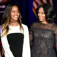 From left, Malia Obama, Michelle Obama, and Barack Obama stand on stage