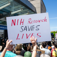A sign is held in a crowd that says "NIH Research Saves Lives"