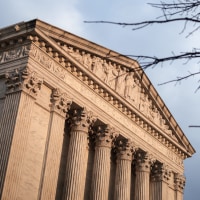 The exterior of the Supreme Court building on the left, a tree is seen on the right