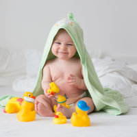 Cute little baby toddler boy, playing with rubber ducks after bath in bed