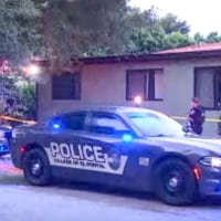Police cars with lights on in front of a house outside