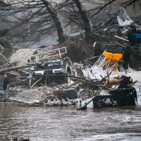 A member of the public stands next to overturned vehicles.