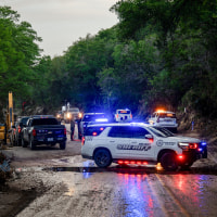 Police cars and officials on a muddy road