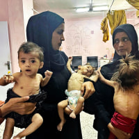 Mothers hold their emaciated children at Nasser Hospital in Khan Yunis, Gaza