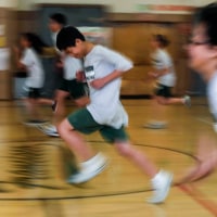 Students in gym uniforms run across the gym floor, there is motion blur