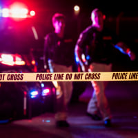 Two police officers behind crime scene tape