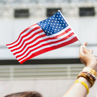 A split composite image of someone holding an American flag, left, and Jen Psaki.