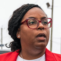LaMonica McIver walks past a chainlink fence gate outside