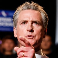 Gavin Newsom speaks at a podium with a red sign on it that reads "Election Rigging Response Act"