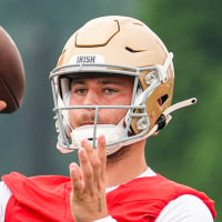 CJ Carr prepares to throw a football on the field, wearing a helmet