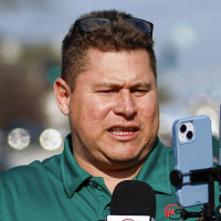 Mario Guevara holding a microphone and an iPhone via a tripod