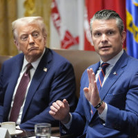 Donald Trump, left, and Pete Hegseth sit at a table as Hegseth speaks