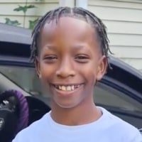 Sakir Everett smiles while standing near a car with the passenger car door open