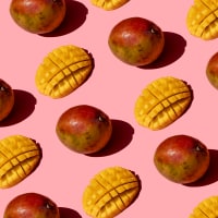 Whole and chopped mango pattern on pink background.