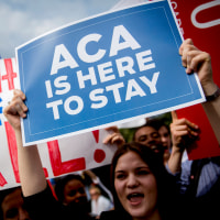 Demonstrators hold signs.