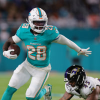 Oct 30, 2025; Miami Gardens, Florida, USA; Miami Dolphins running back De'Von Achane (28) runs for a gain past Baltimore Ravens linebacker Mike Green (45) during the first quarter at Hard Rock Stadium. Mandatory Credit: Sam Navarro-Imagn Images