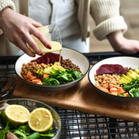 Female Preparing Aesthetically Pleasing Salad Bowls Adding Dressing on Top To Tie Flavors Together