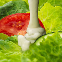 Ranch dressing pouring on salad