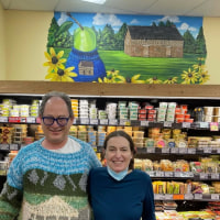 Sam Barsky and his wife stand in front of the mural painted in his honor at the Pikesville Trader Joe's.