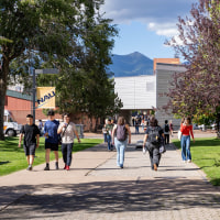 Students walking on Northern Arizona University campus with San Francisco Peaks background