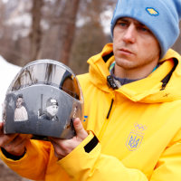 Ukraine's skeleton racer Vladyslav Heraskevych holds his helmet, which depicts victims of his country's war with Russia, in Cortina d'Ampezzo.