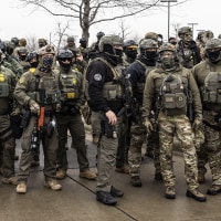 Federal Agents stand guard outside an ICE facility during a protest following the fatal shooting of Renee Good. 