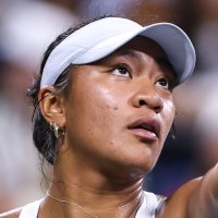 Destanee Aiava tosses up a tennis ball on the court