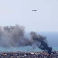 A Middle East Airlines aircraft takes off from the airport in Beirut as smoke rises from the site of an Israeli air strike that targeted an area in the southern suburbs of the Lebanese capital on March 17, 2026.