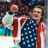 Jack Hughes of Team United States celebrates after their gold-medal win with an American flag draped over his back
