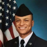 Army members carry a casket across an aircraft tarmac as Donald Trump and company stand to watch while saluting