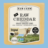 A photo illustration showing Raw Farm Raw Cheddar Cheese packaging and shredded cheese packaging next to one another on top of a blue background