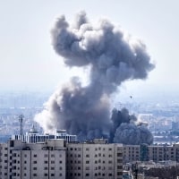 A plume of smoke rises over buildings