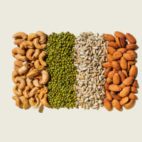Various kinds of vegan protein sources on beige background. Nuts and legumes (green mung beans, cashew nuts, almonds, sunflower seeds). Flat lay, top view