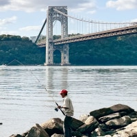 A man fishes in the Hudson River in front of the George Washington Bridge in New York City in 2024.