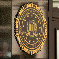 The exterior of a government building with the DOJ seal on its facade.