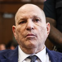 Harvey Weinstein sits at a table in court