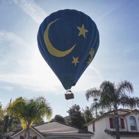 A hot air balloon in the sky above a house