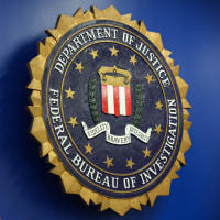 The logo of the Federal Bureau of Investigation hung on a blue wall next to an American flag