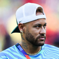 Neymar walks on the soccer field holding a soccer ball