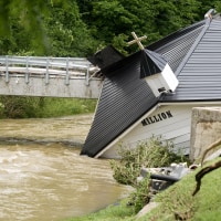 A white church building falling into a rushing river.