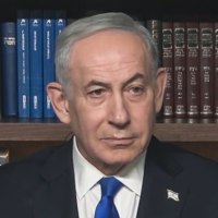 Benjamin Netanyahu sits in front of a bookshelf