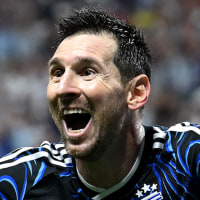 Lionel Messi yells with his arms outstretched while running on the field in celebration