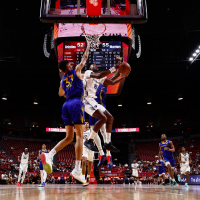 Basketball players rivaling for a ball in front of the basket.