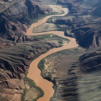 An aerial view of the Grand Canyon landscape with the Colorado River winding through it.